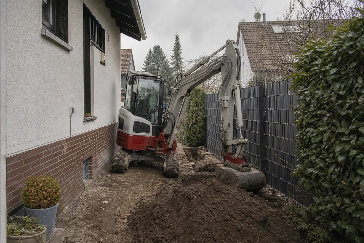 Kompaktbagger in einer engen Garteneinfahrt